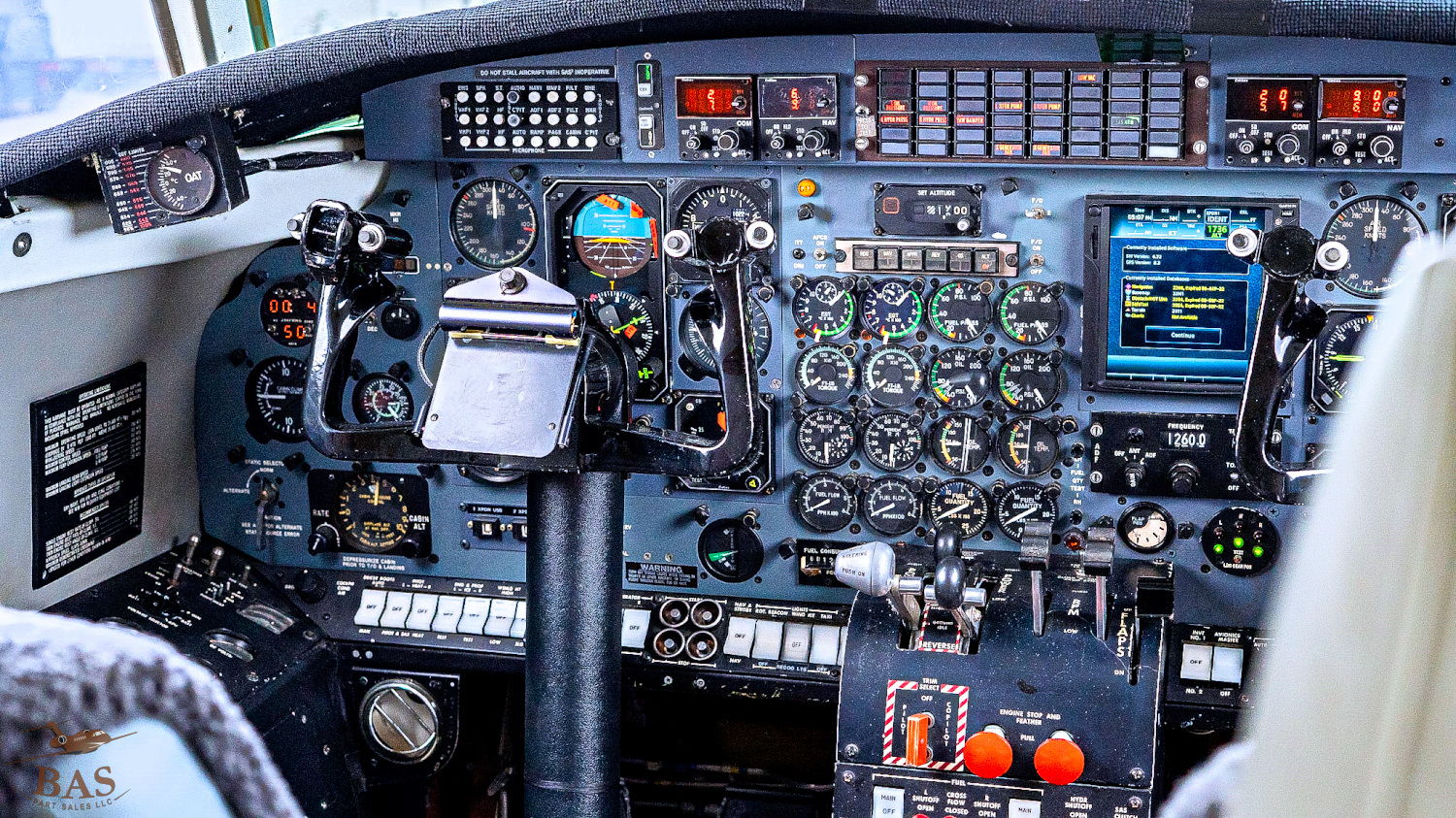 Airplane cockpit with numerous controls, gauges, and screens displayed.