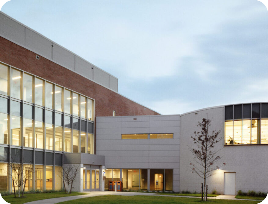 Modern building exterior with large windows and a landscaped area.