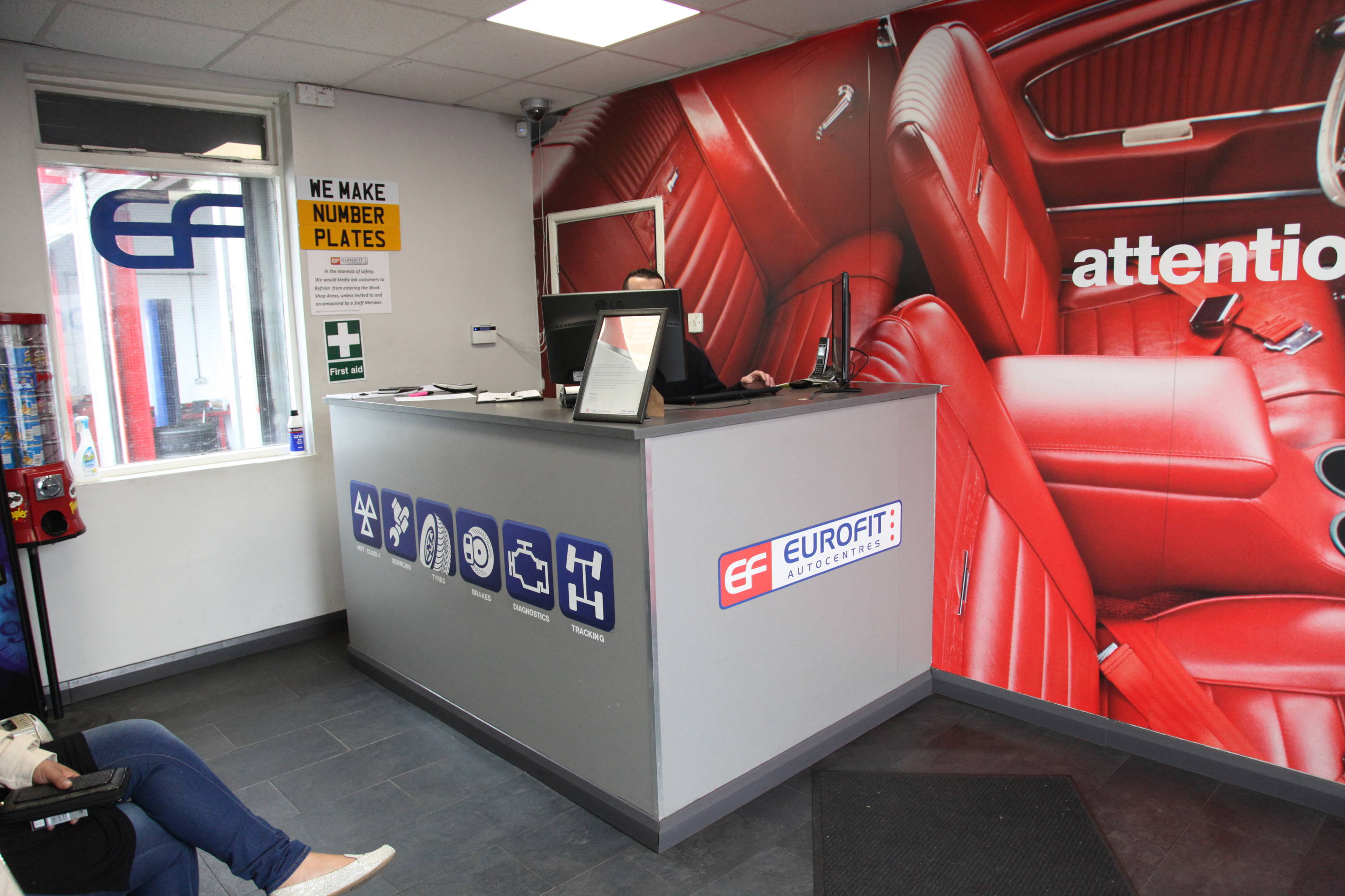 Car garage waiting room with reception desk and customer sitting down 