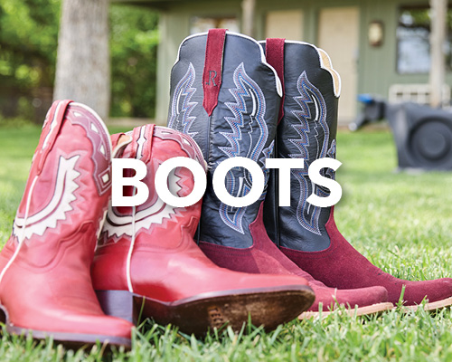 Red and black cowboy boots on grass with the word 