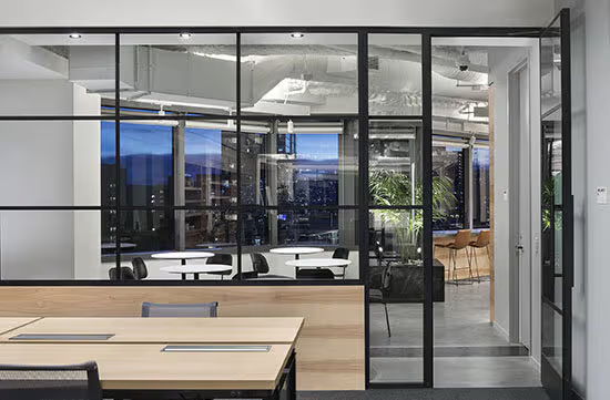 Modern office interior with glass walls and wooden furniture.