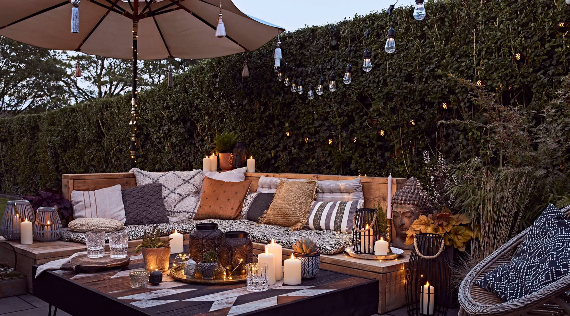 Outdoor space illuminated at night by festoons, candles and lanterns.