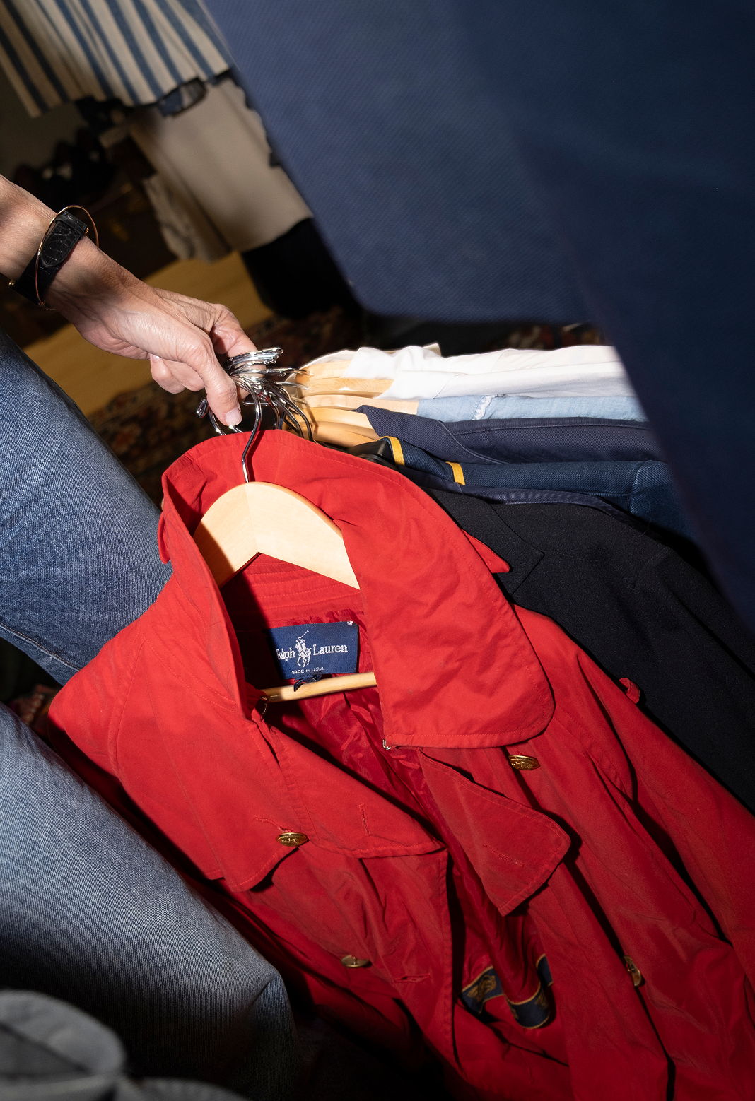 A person holding a red coat on a hanger.