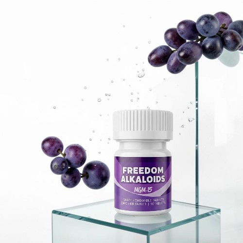 Bottle of Freedom Alkaloids beside grapes on a glass surface.
