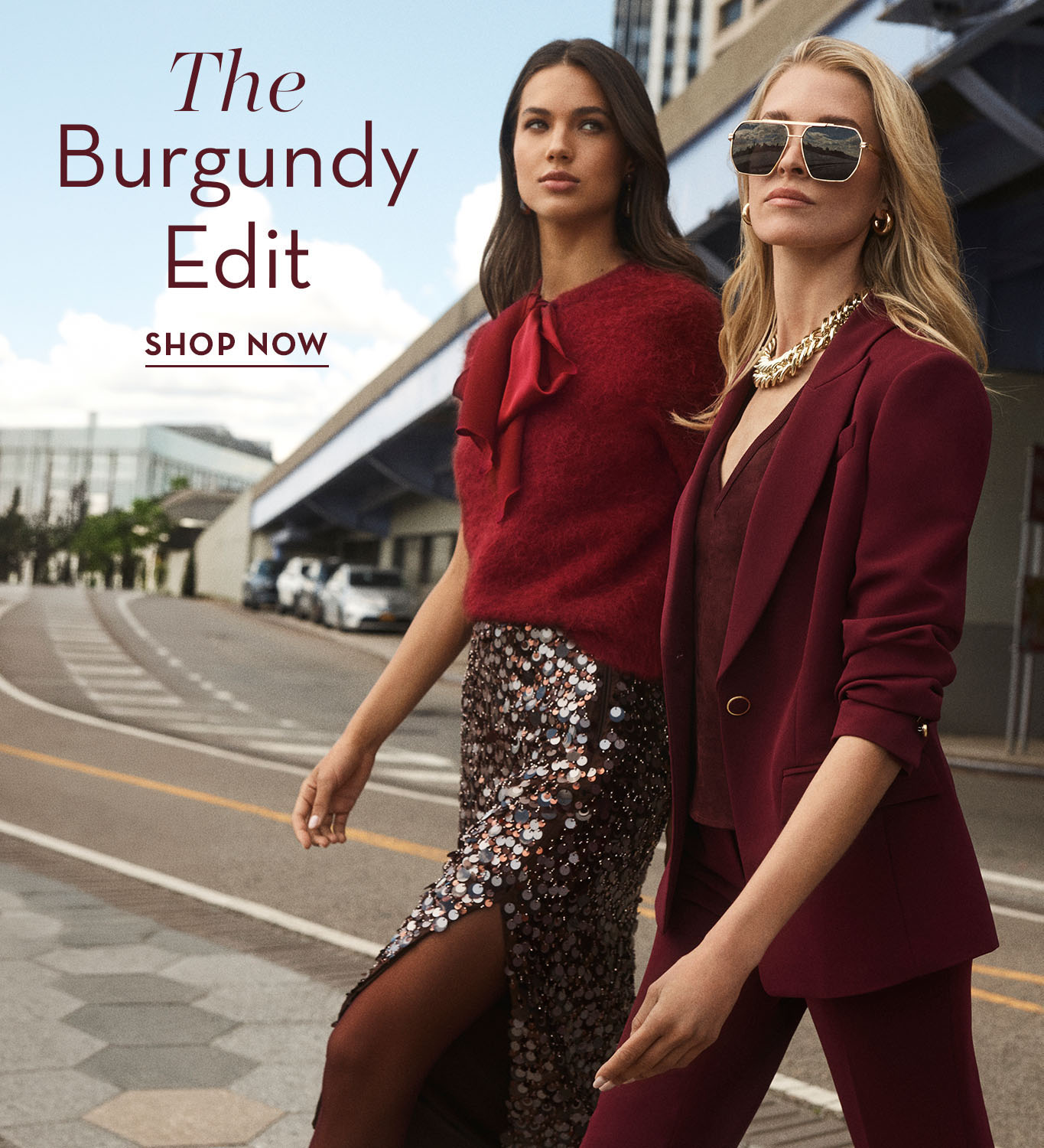 Two women modeling burgundy outfits in an urban setting with promotional text.