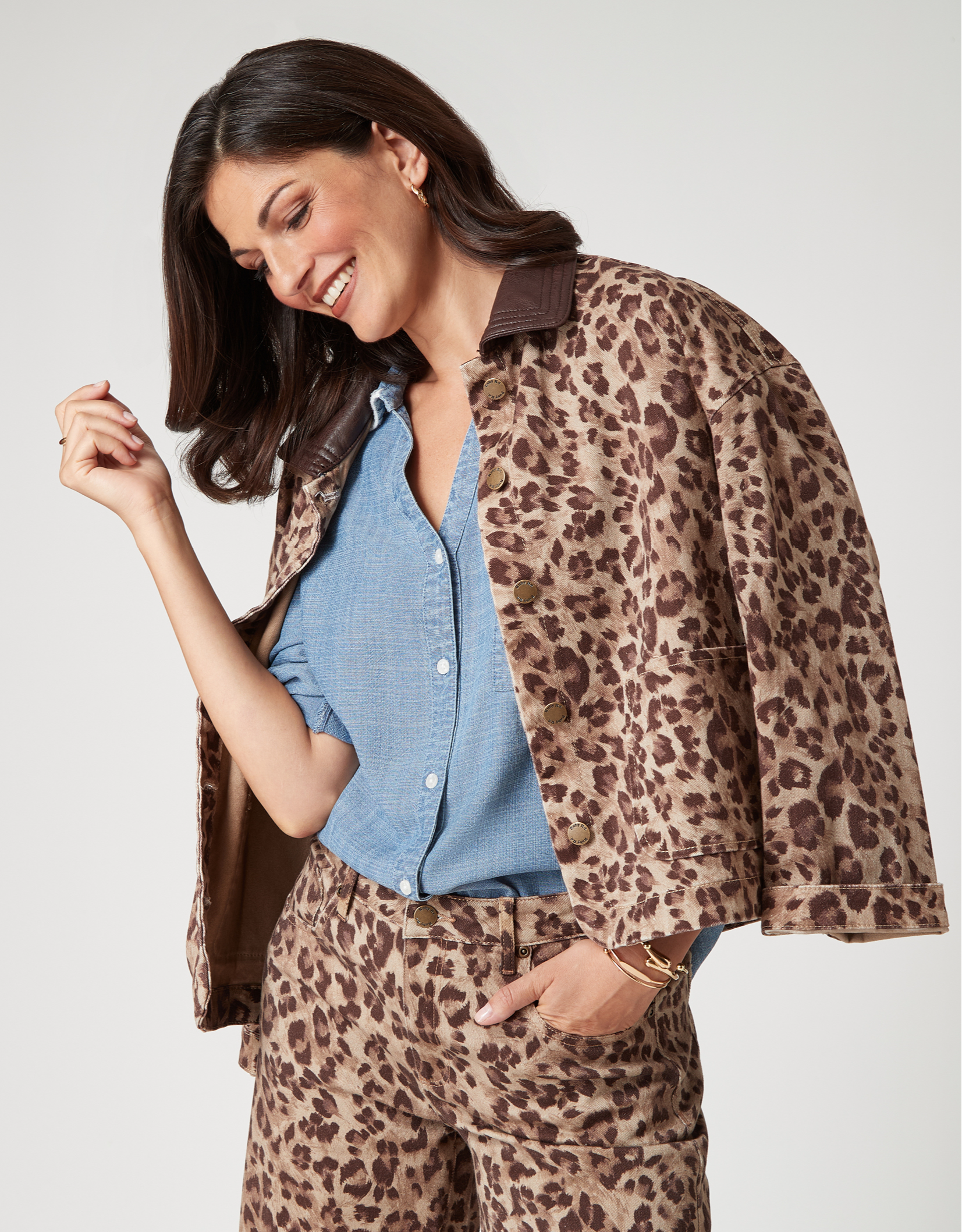 Woman smiling in leopard print outfit with a denim shirt.
