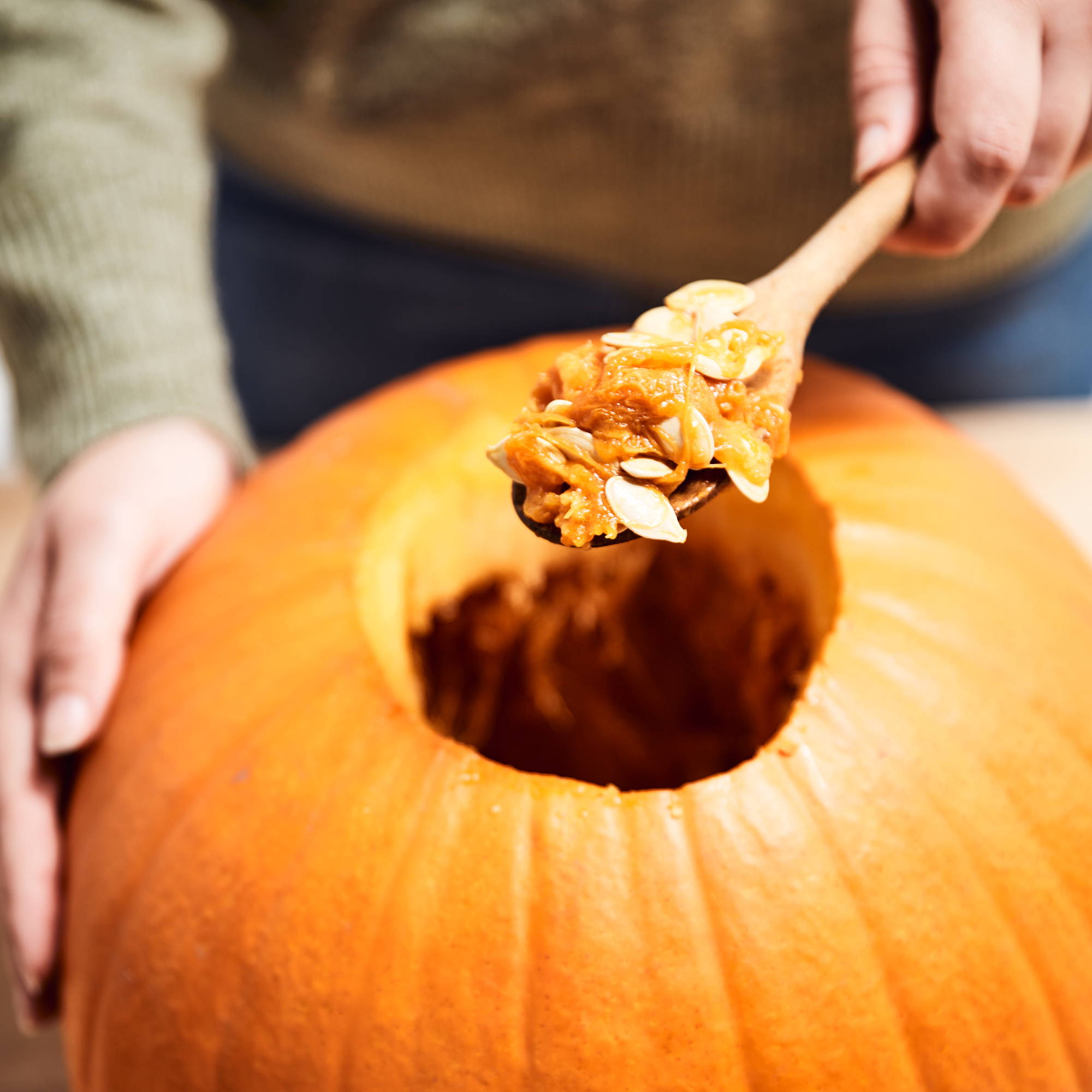 Person scooping pumpkin flesh out of the top.