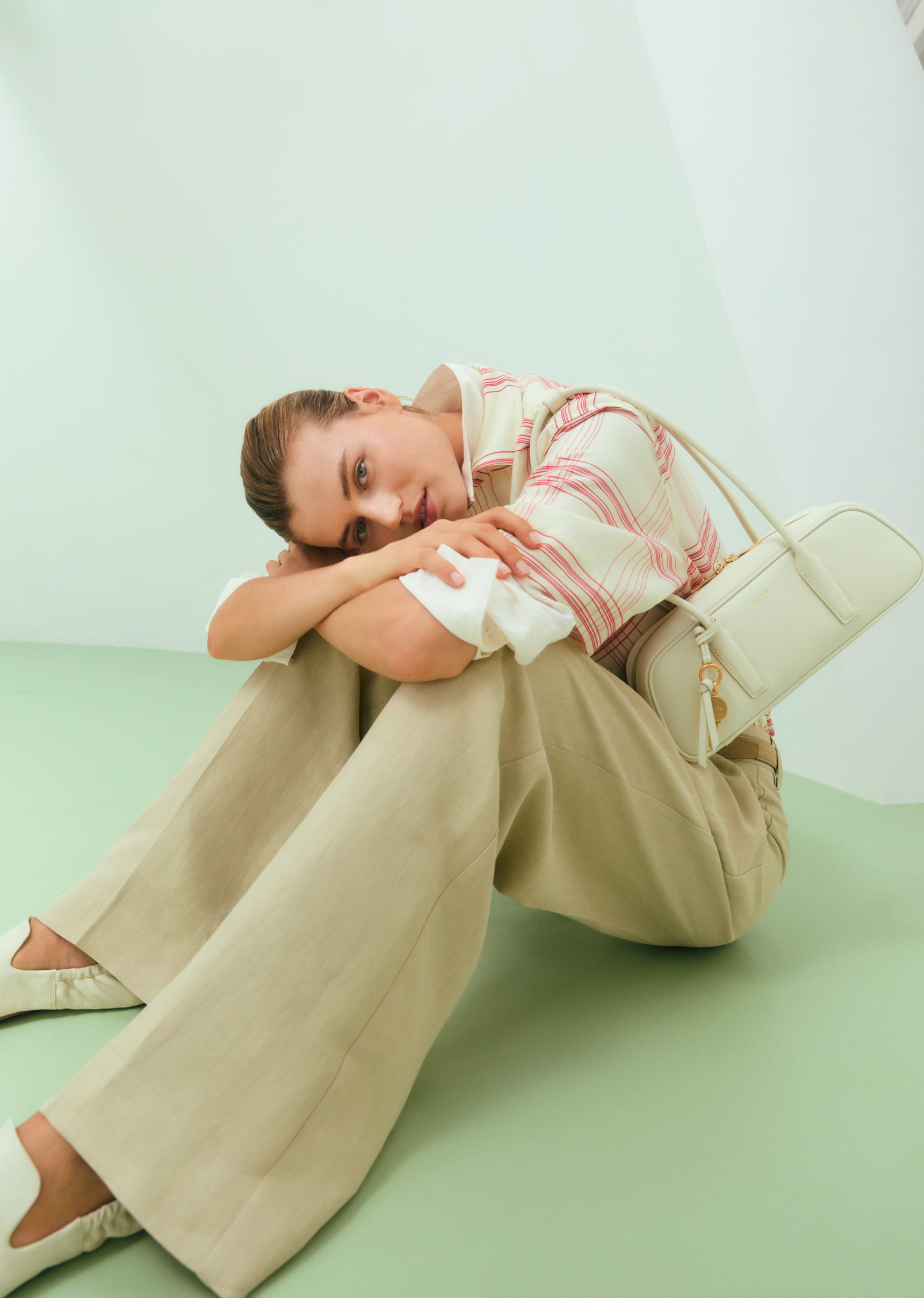 A person sitting on a green floor, leaning against their knees.
