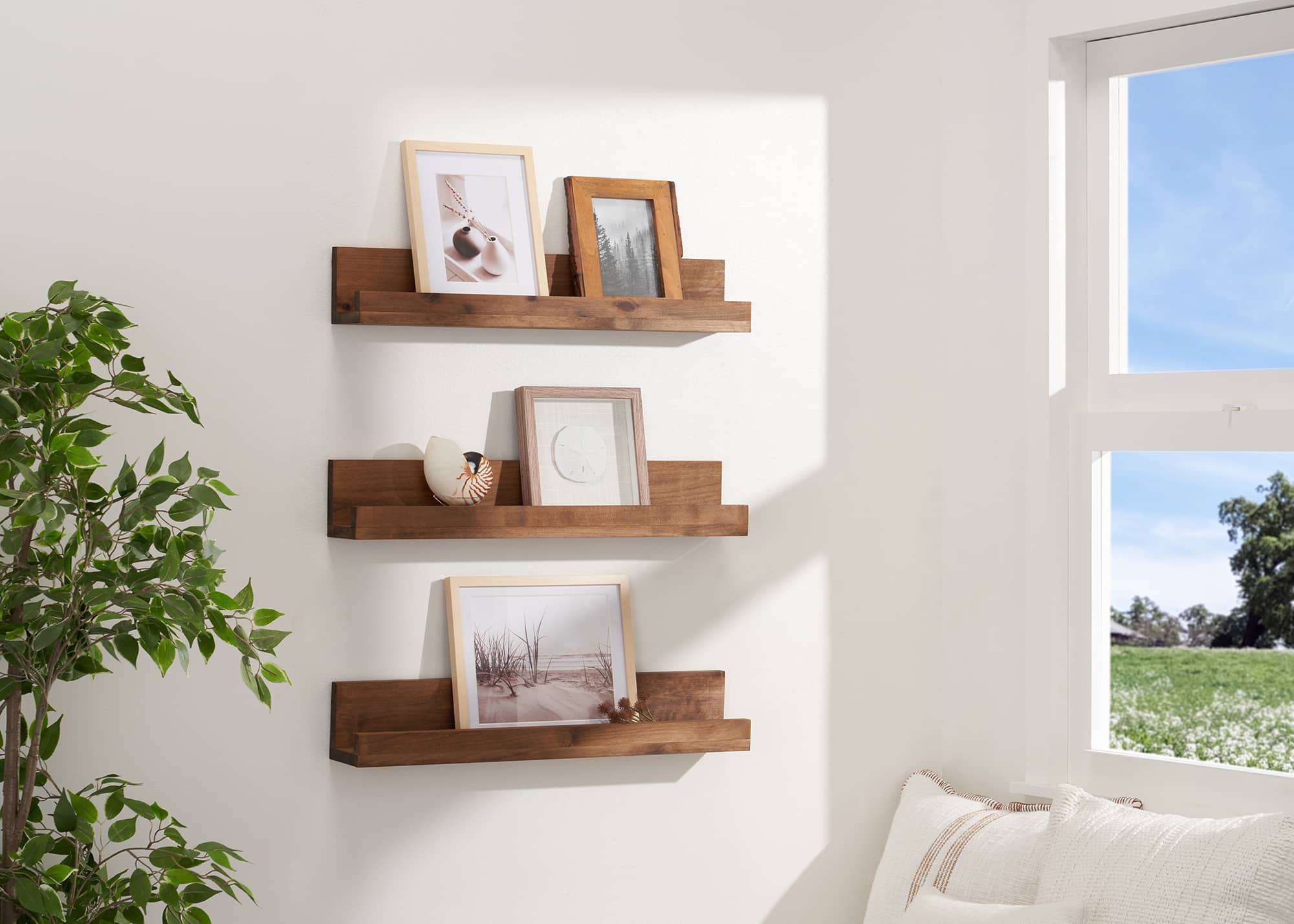 3 floating wall shelving rack on a living room wall, filled with picture frames, trinkets and photo frames