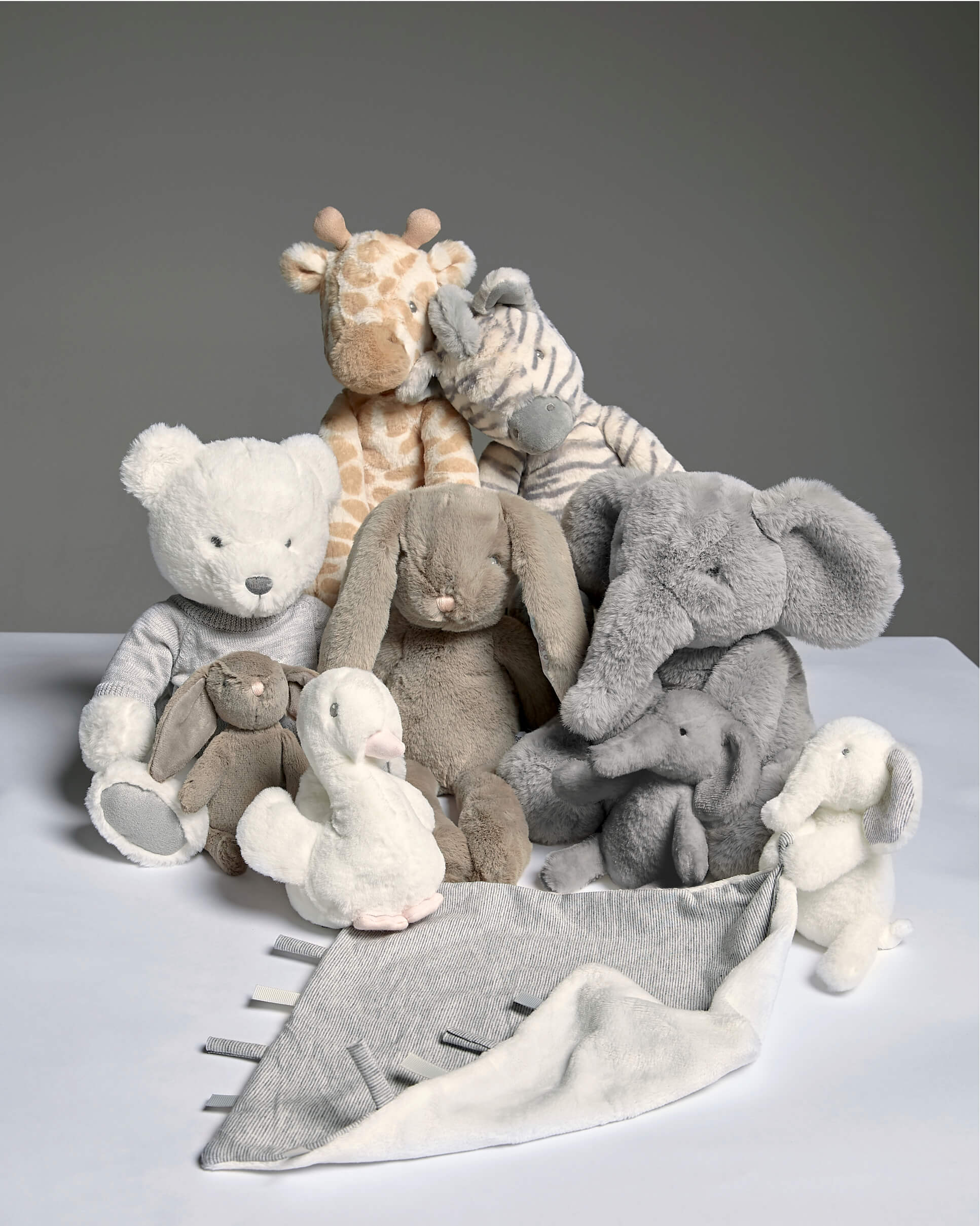 A group of plush toys including a bear, elephant, giraffe, and bunny.