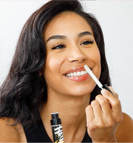 Smiling woman applying Lip Heal in a beauty setting.