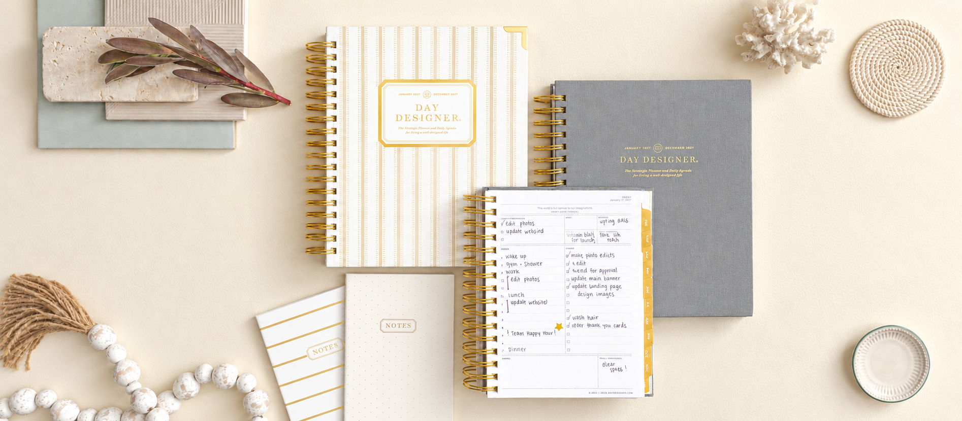 stacked daily day designer planners, gray, stripped 2027 planners, notebooks, beige background, beads, coral, tape, dried leafs
