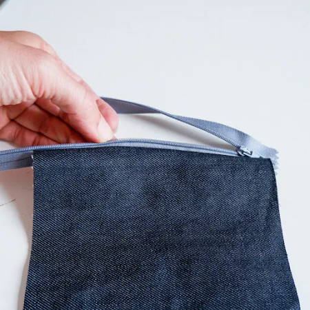 A piece of denim fabric attached to one side of a zipper