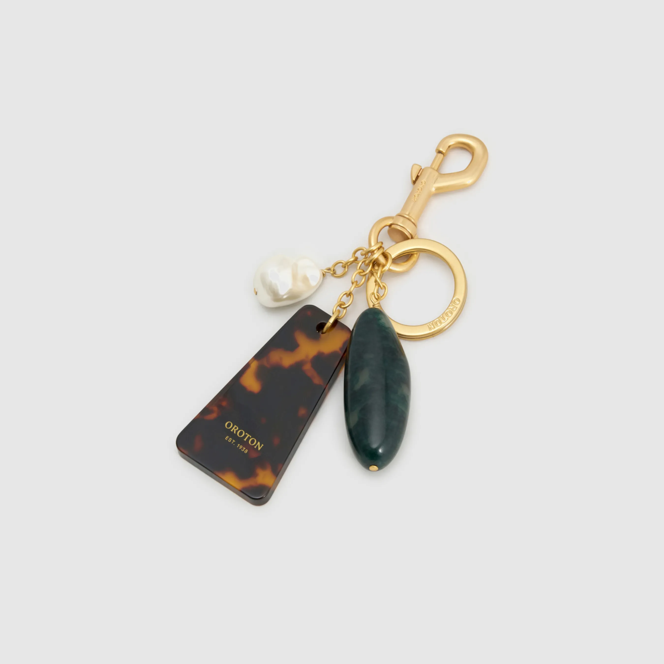 Gold keychain with tortoiseshell and green gemstone charms.