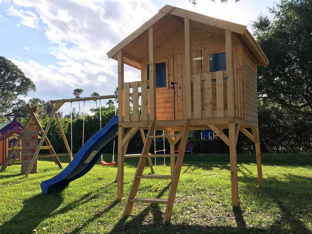 Little Tower Playhouse with stairs and a slide on a sunny day on green lawn | DIY kids playhouse kits by WholeWoodPlayhouses