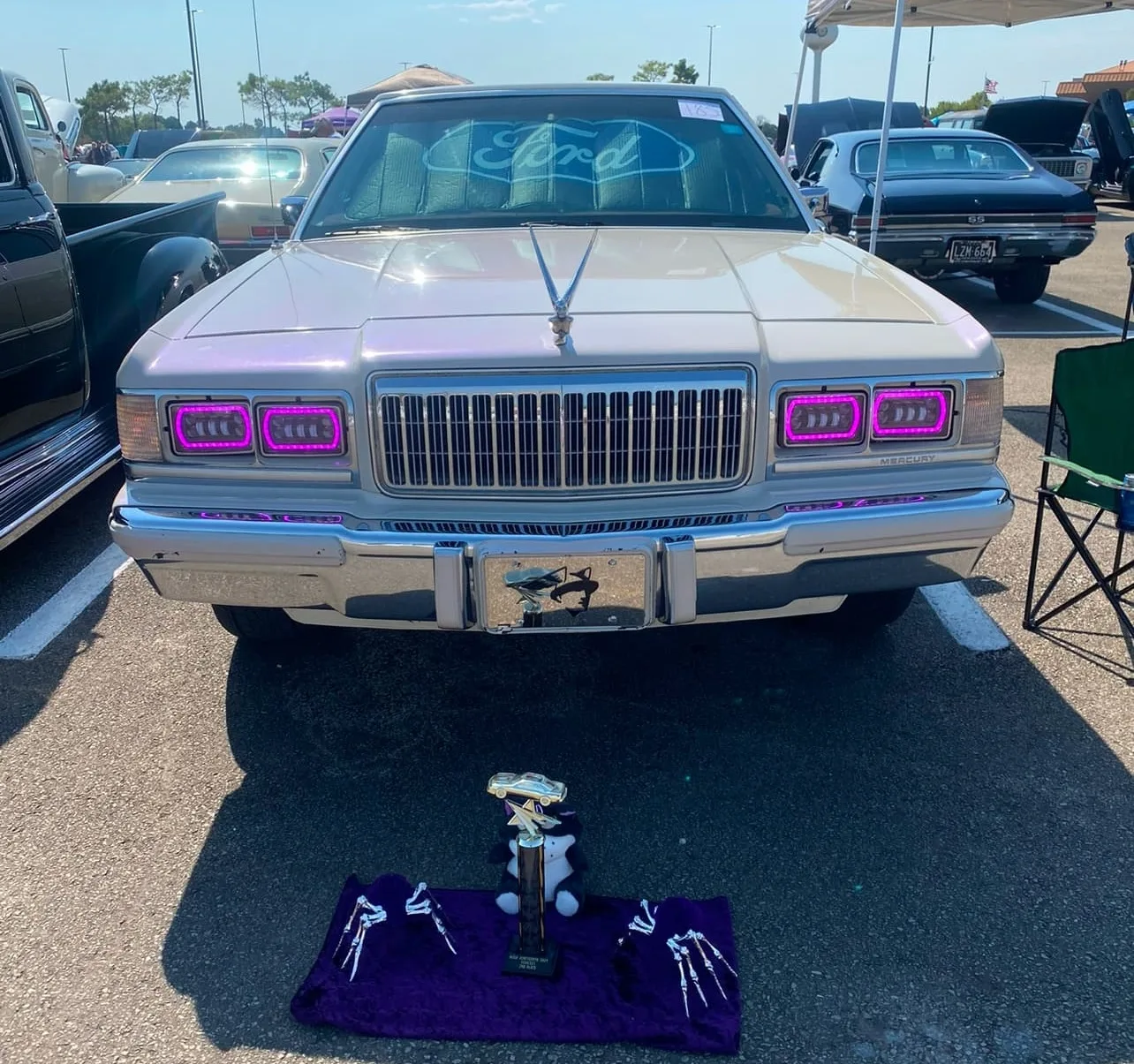 White Mercury Grand Marquis front view with purple headlights at car show