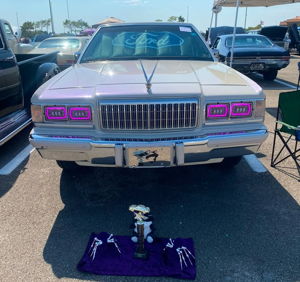 White Mercury Grand Marquis front view with purple headlights at car show