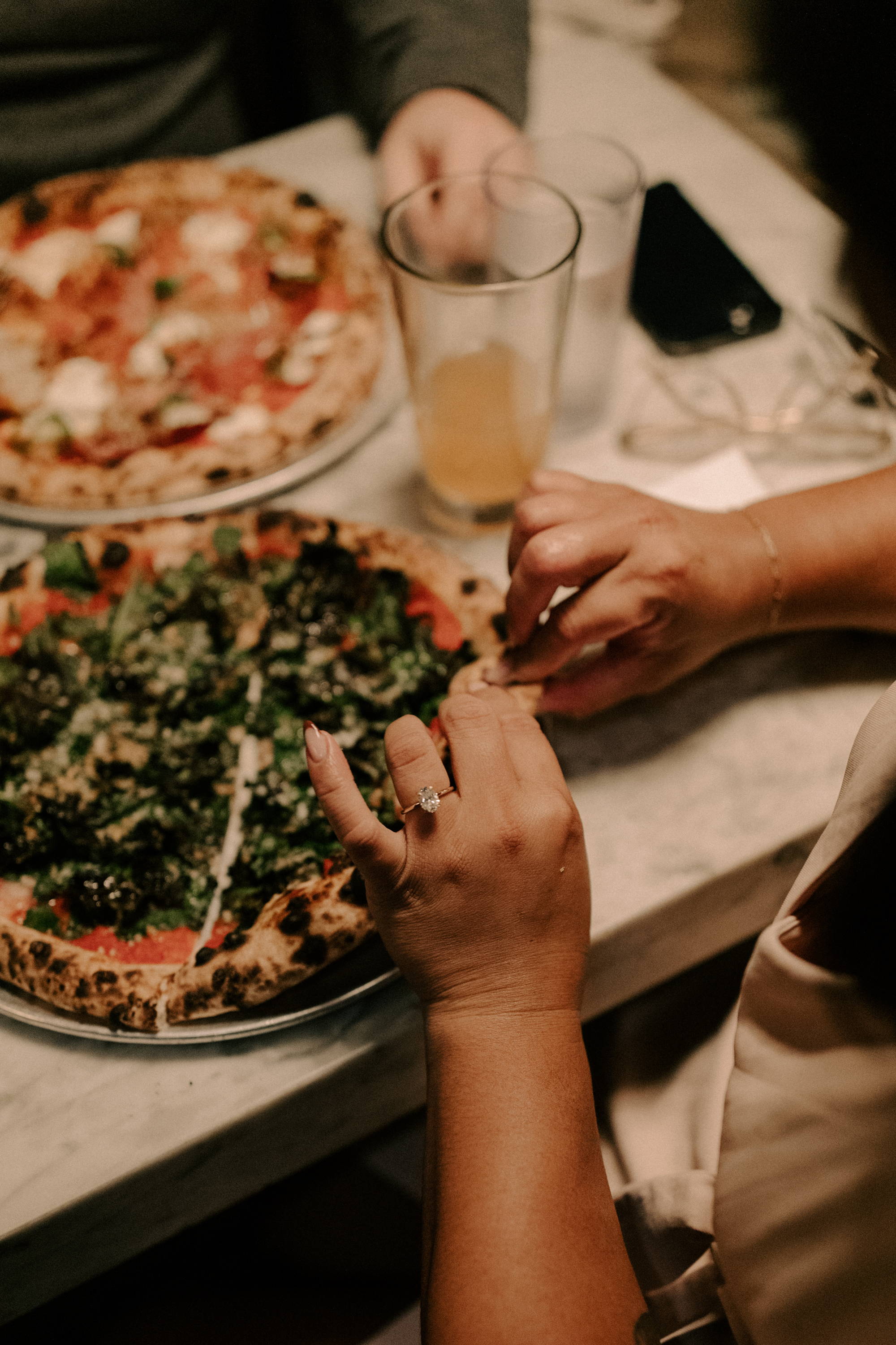eating a pizza with engagement ring in foreground