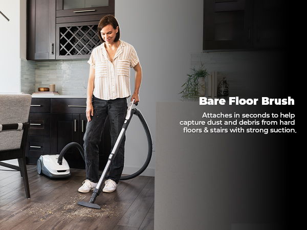 Person using a vacuum with a bare floor brush on hardwood flooring.