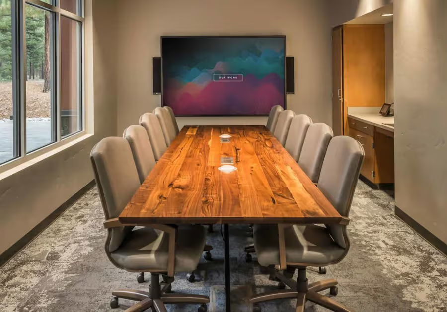 A modern conference room with a large wooden table and chairs.