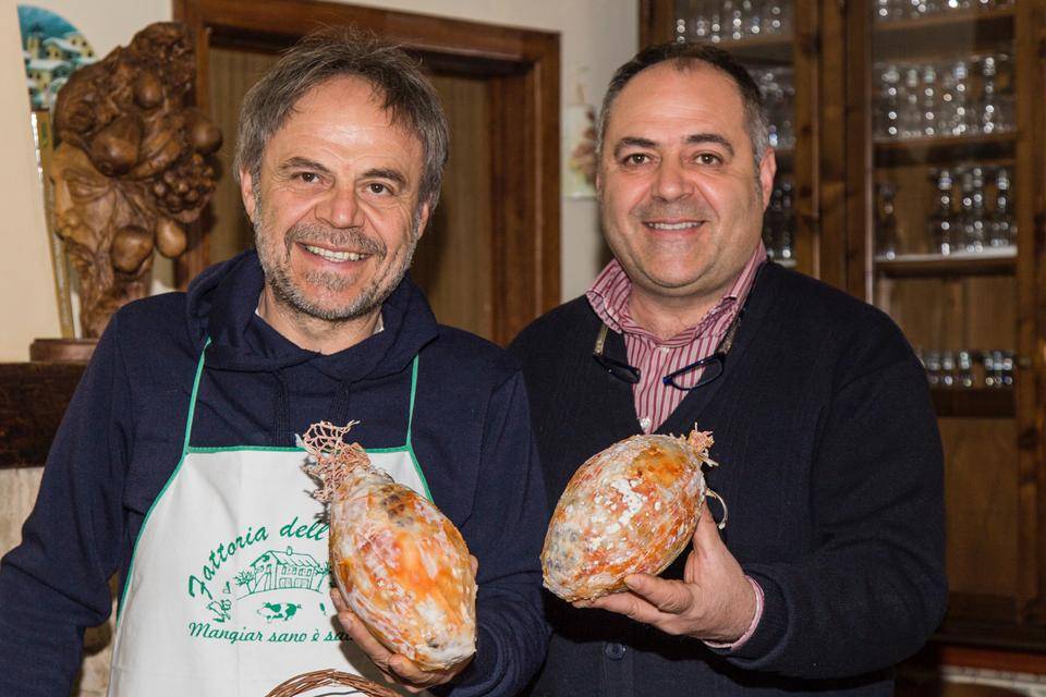 Two brothers proudly display their handmade aged salumi