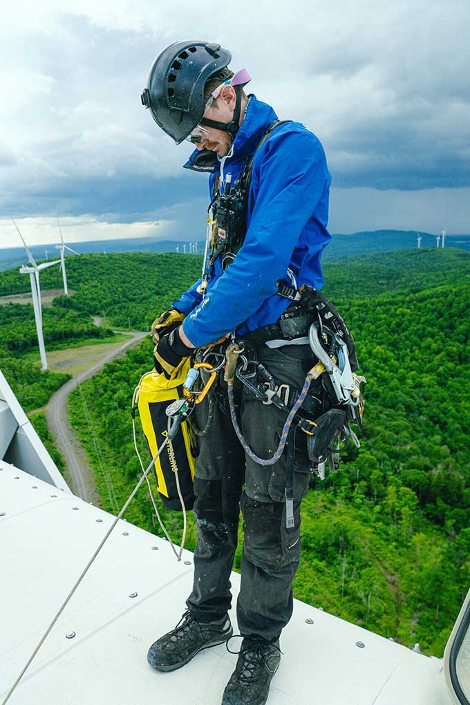 Rope technician in safety gear working on a wind turbine.