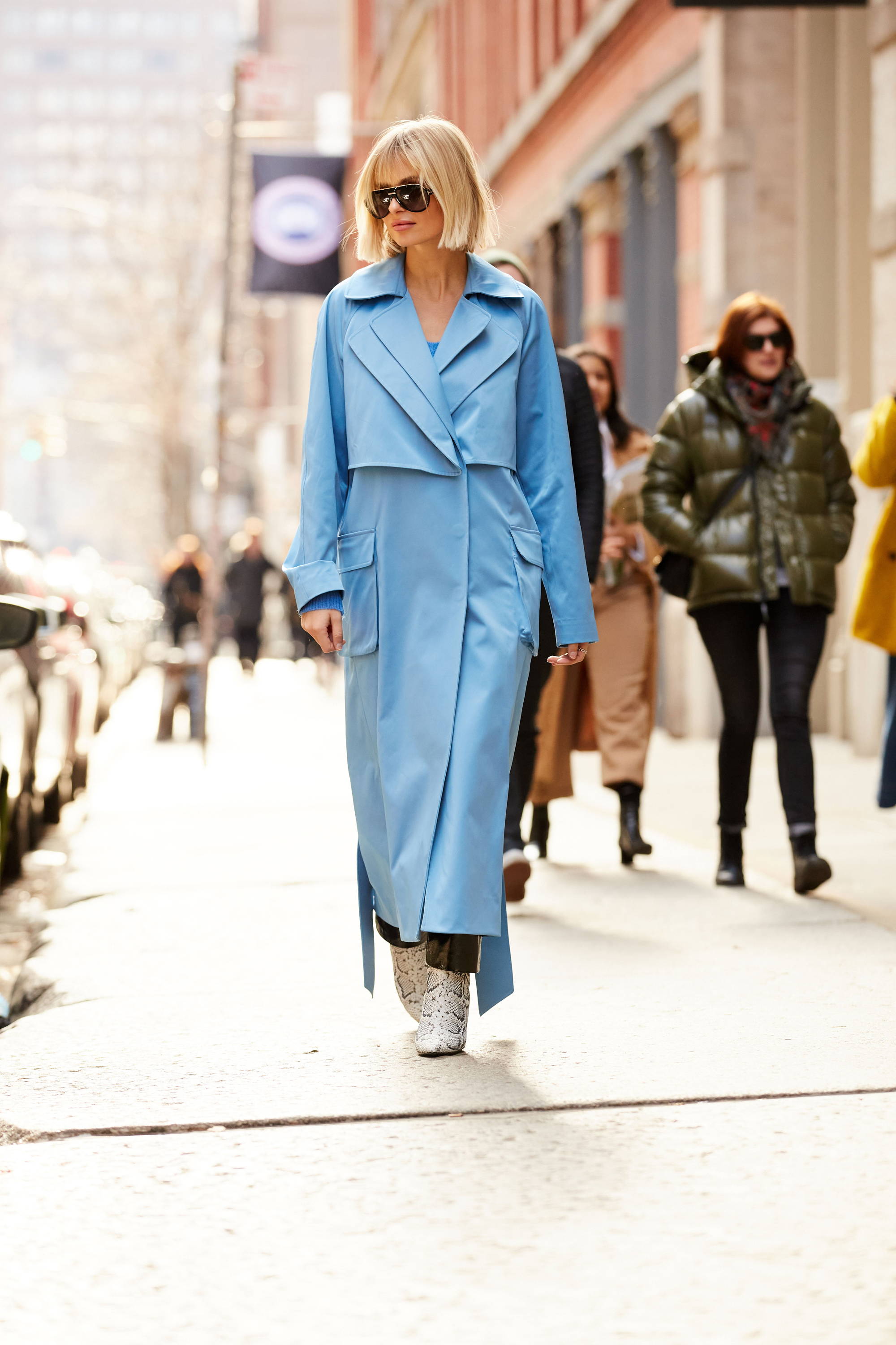 A woman in a blue coat walking on a city street.