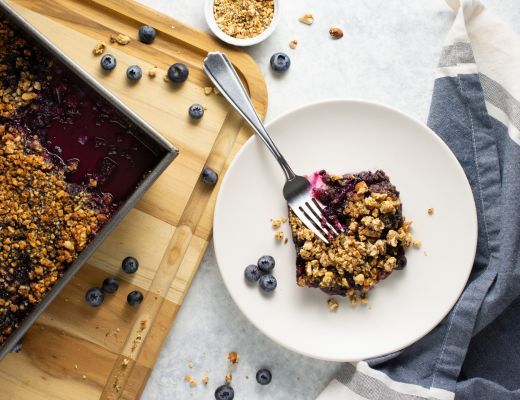A slice of blueberry crumble on a plate with a fork.