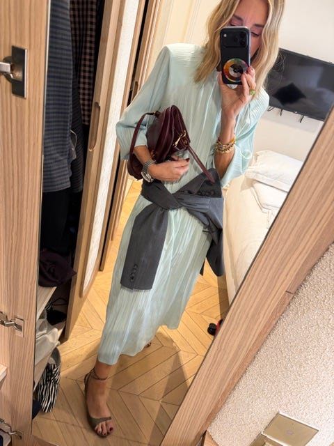 Person taking a mirror selfie in a light green dress.