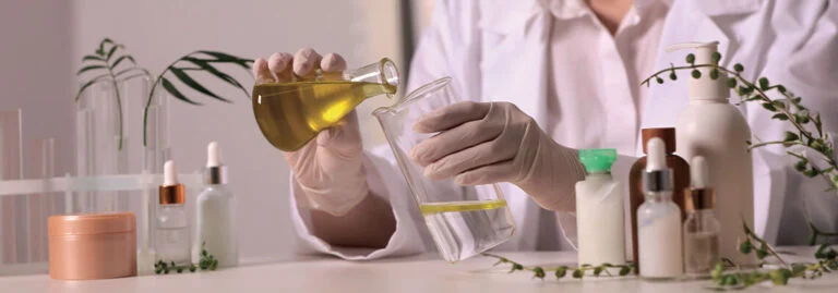 Scientist pouring liquid into a beaker surrounded by various bottles and plants.