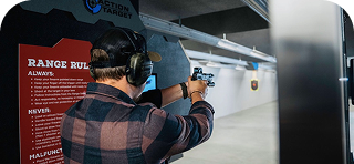 Person aiming a firearm at a shooting range target.