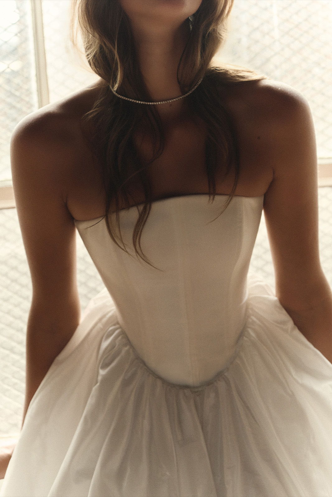 A close-up of a person wearing a strapless white dress.