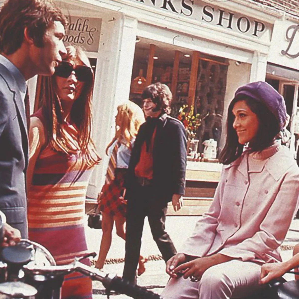 Group of people in 1960s fashion on a street.