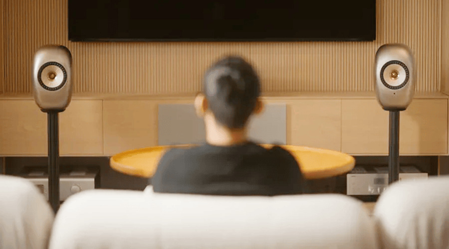 Person sitting on a couch, facing speakers and a television.