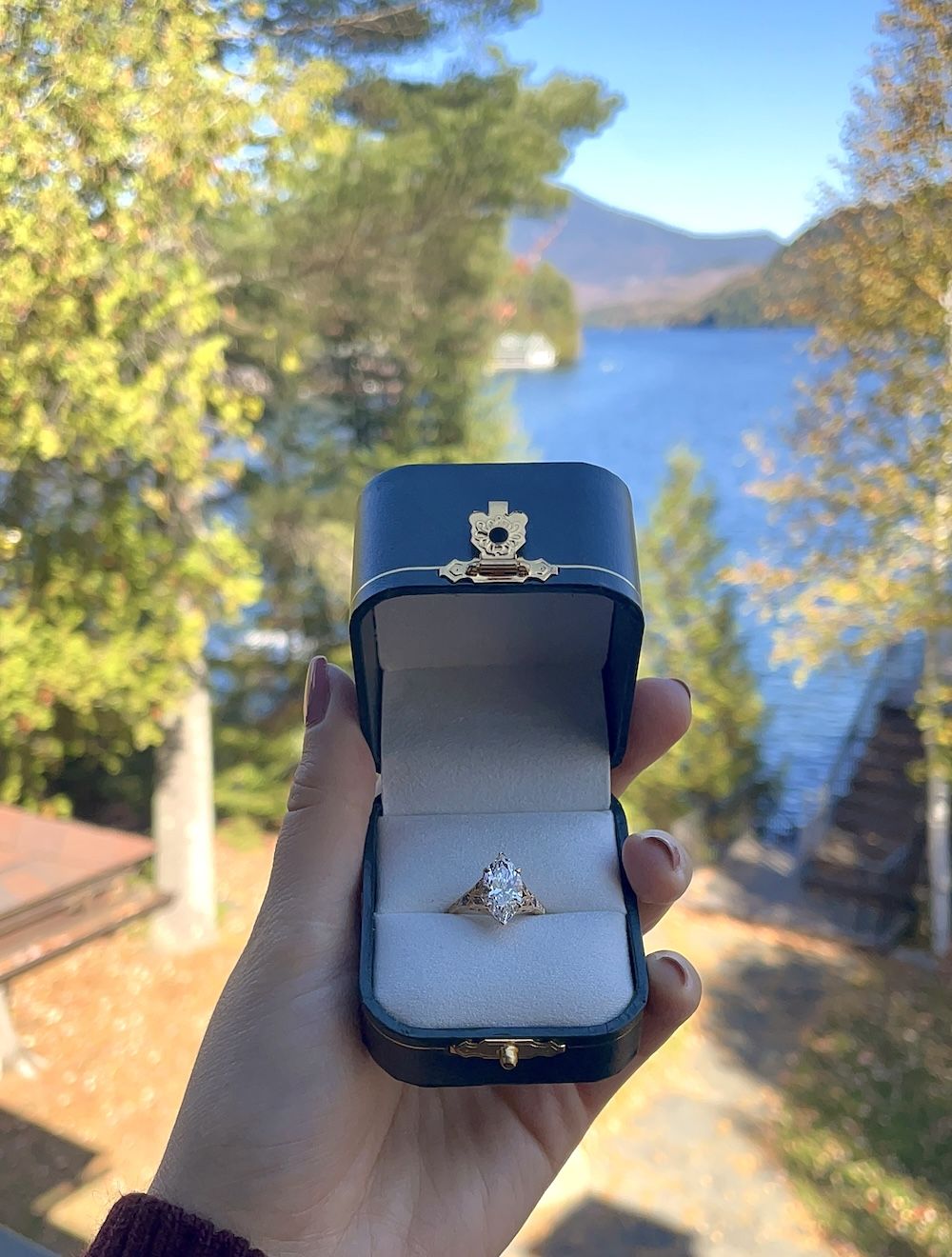 engagement ring in box in front of lake placid, ny