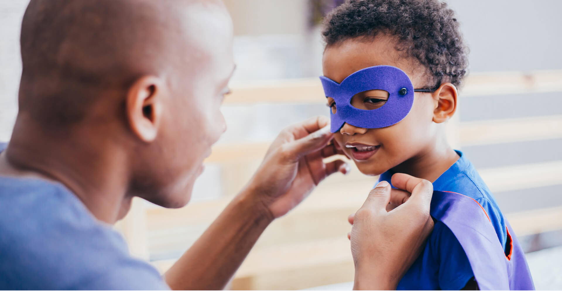 Man Putting On Superhero Mask On Child