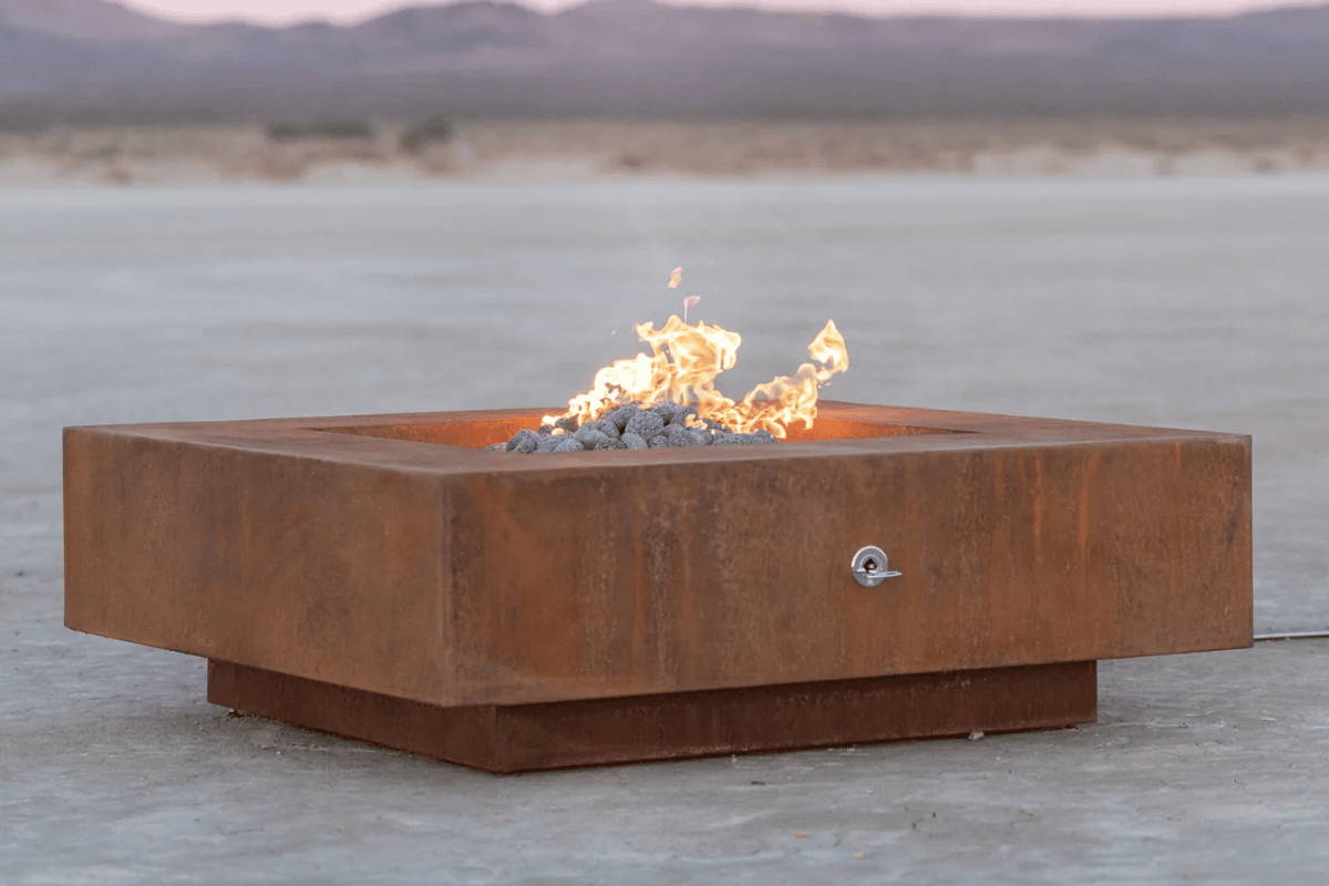 Boxhill's Cabo Square Metal Fire Pit features a natural brown patina and grey lava rocks..