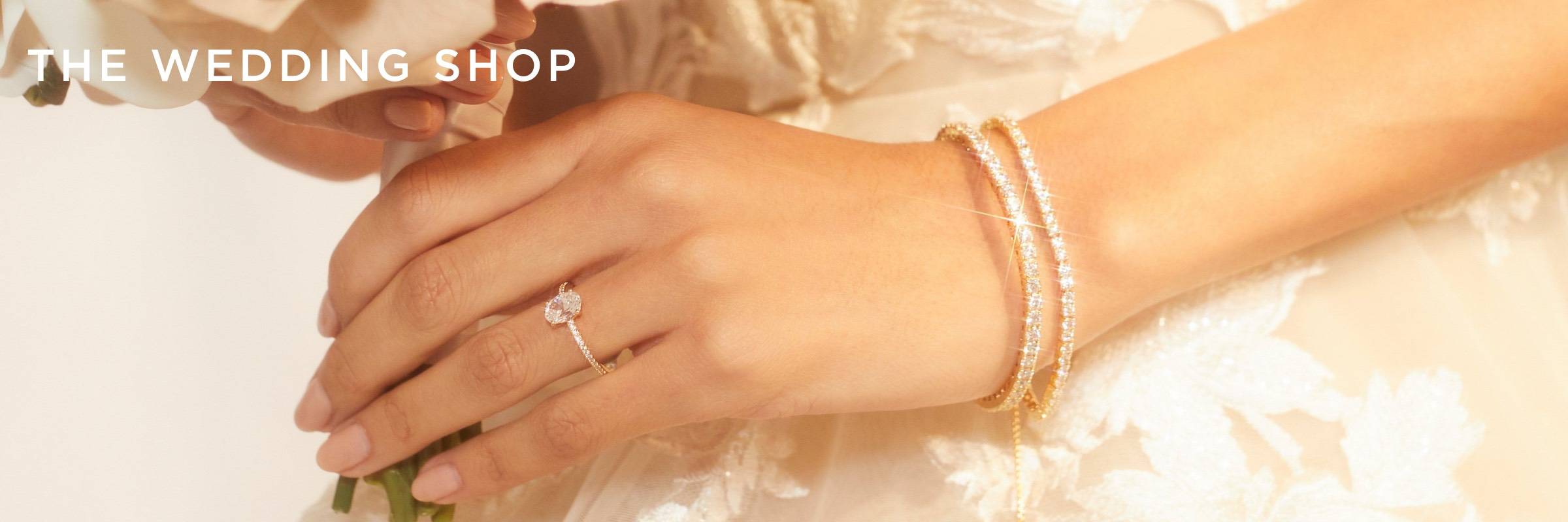 The Wedding Shop. Image of a bride's hand with an oval solitaire CZ ring and two CZ tennis bracelets.