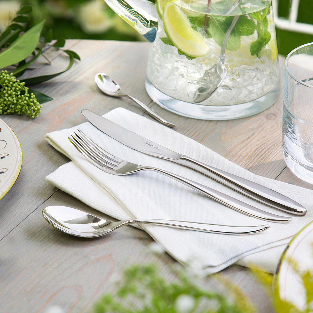 Table setting with Hidcote Bright cutlery, napkin, and glassware on a wooden table.