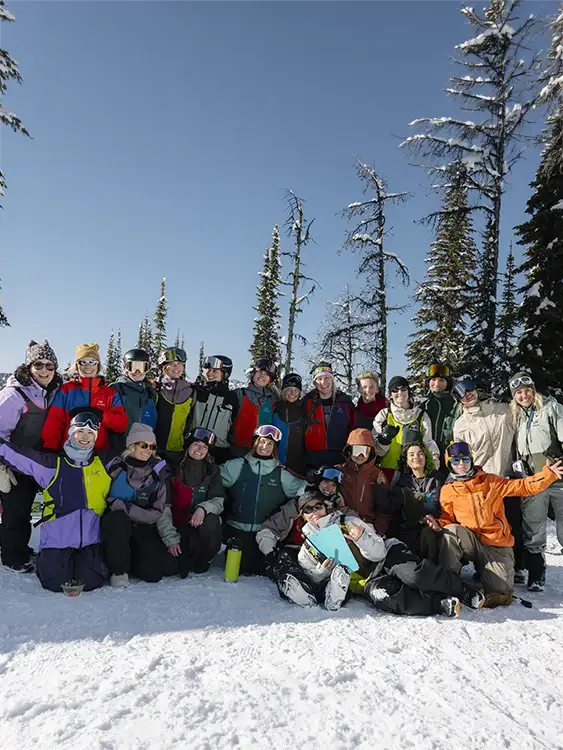 SGroup of people in winter attire posing on snow-covered mountain.