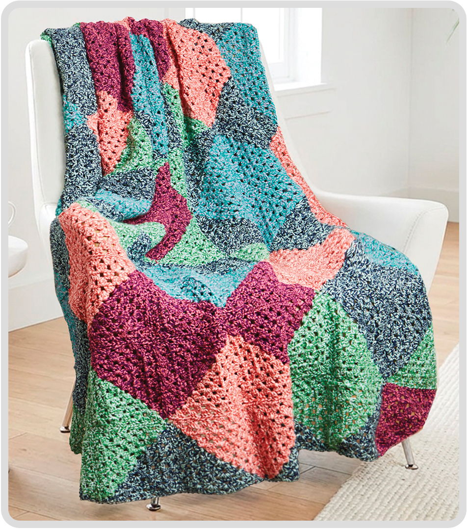 Colorful crocheted blanket draped over a chair in a bright room.