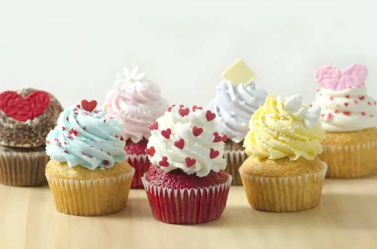 Image of different coloured cupcakes with frosting and various different toppings.