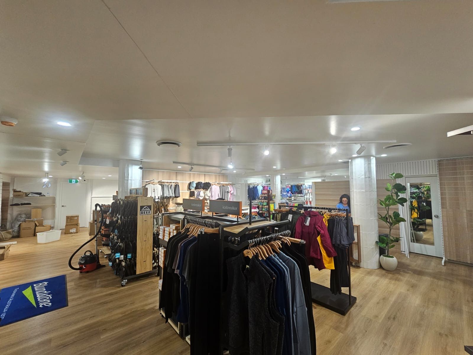 Clothing store interior with racks displaying various garments and bright lighting.