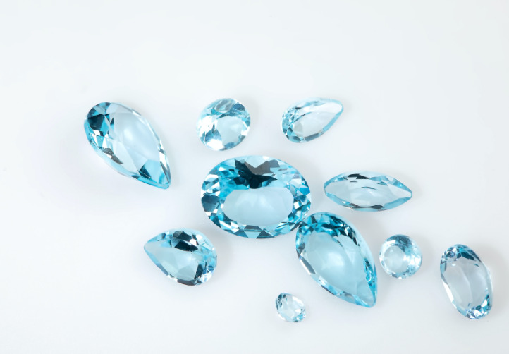 Blue Topaz stones are lying on a white surface.