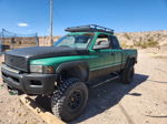 Front quarter view of lifted green and black Dodge Ram with roof rack and off-road tires in desert
