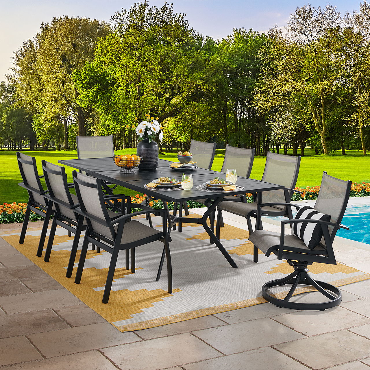 Outdoor dining set with chairs by a pool and greenery in the background.