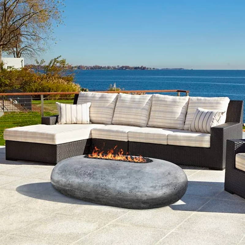 A pebble-shaped outdoor fire pit on a lakeside patio.