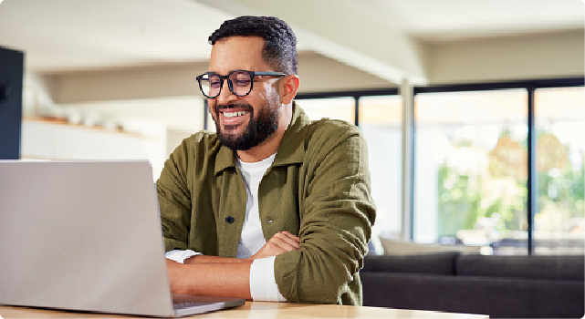 Smiling man using a laptop in a bright, modern living space.