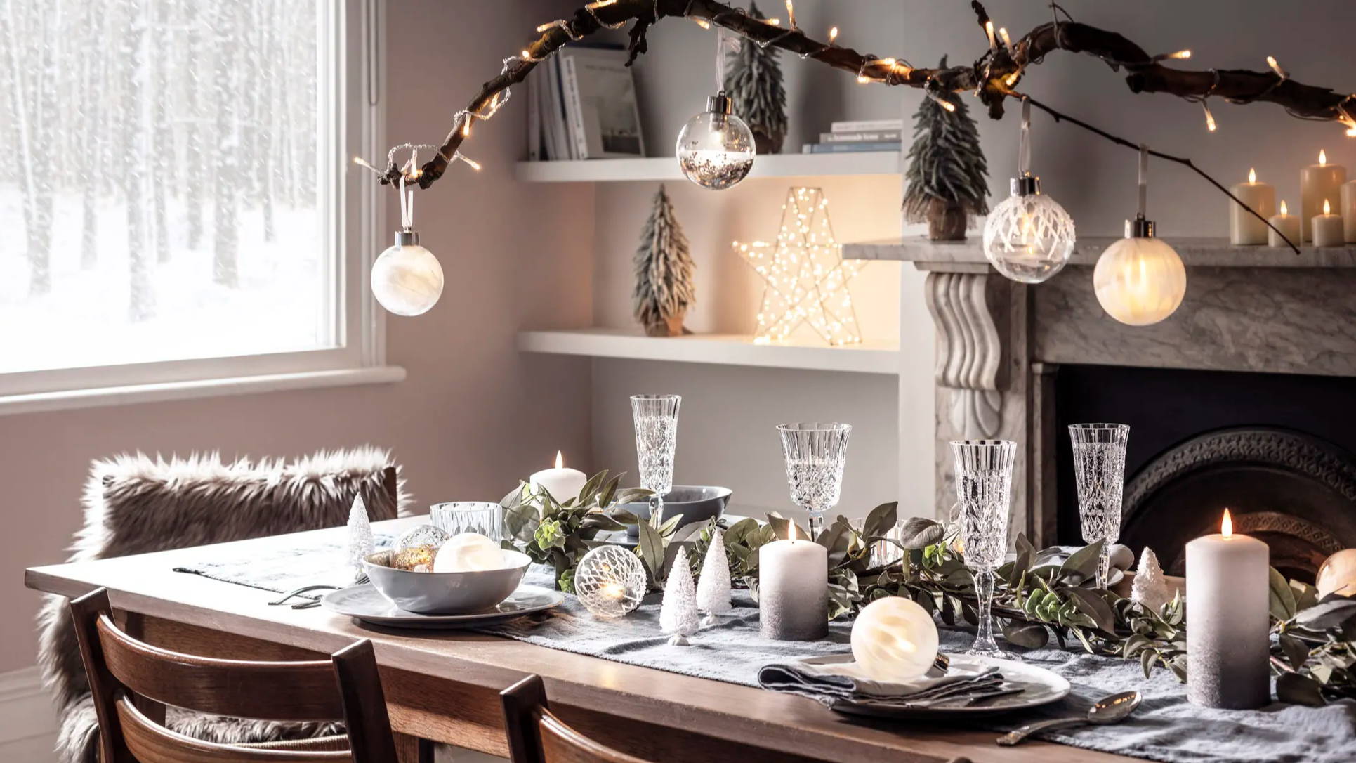 Festive dining table with baubles, candles and mini Christmas trees.