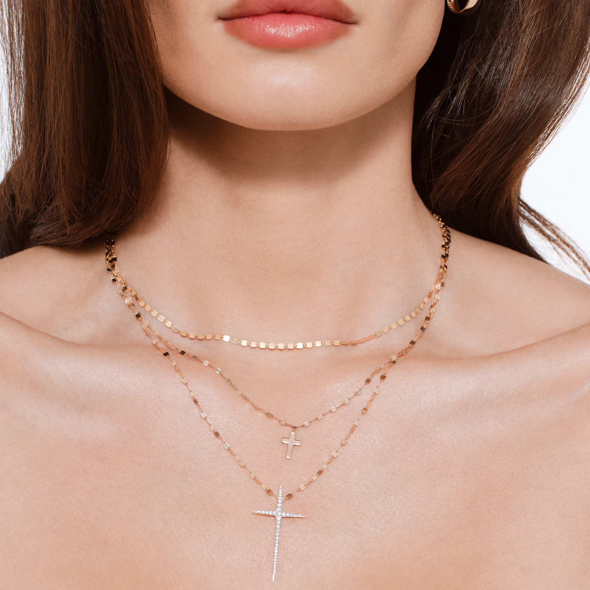 Close-up of a woman wearing layered necklaces and earrings.